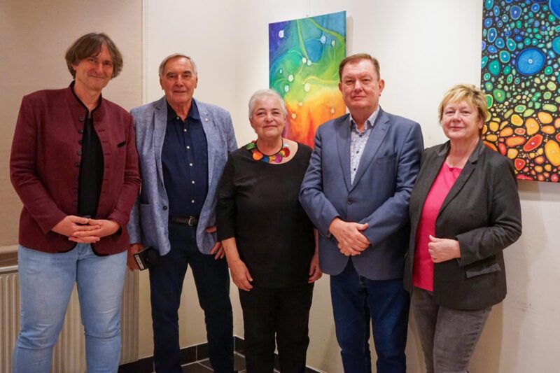 Saxophonist und Sprecher von Even4Sax, neben Niki Patoschka, Sigrid Jonak, Bgm. Herbert Janschka und Gemeinderätin Gaby Janschka vor zwei bunten Bildern der Künstlerin für das Pressefoto