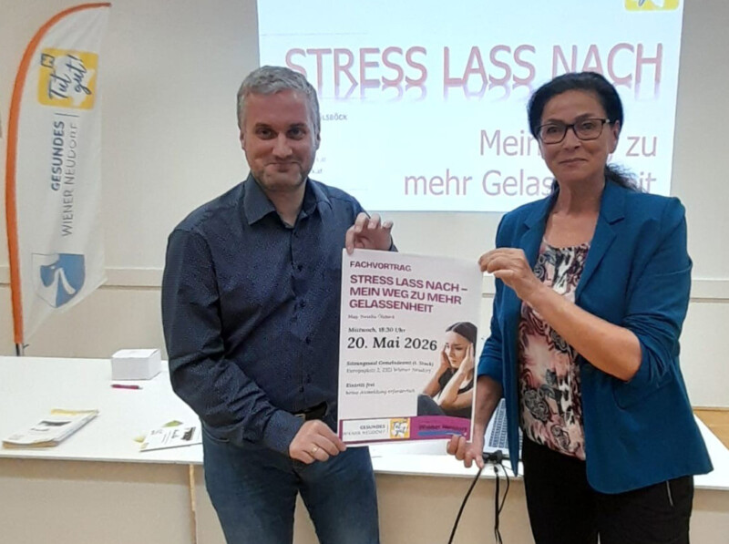 Alexander Bitzan und Mag. Natalie Ölsböck präsentieren das Plakat für den Vortrag im Sitzungssaal