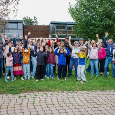 Große Gruppe mit ein paar Kindern im Vordergrund Hortmitarbeiterinnen winken